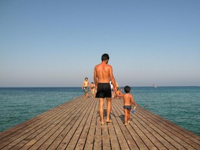 A father walks with his son along a pier in Protaras on the holiday island of Cyprus on August 15, 2010.