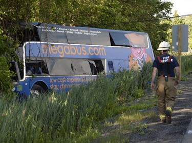 A firefighter attends the scene of an accident where dozens were injured, several seriously, when a tractor trailer and double-decker bus en route from Montreal to Kingston collided on highway 401 near Cornwall, Ont., on Tuesday, June 23, 2015.