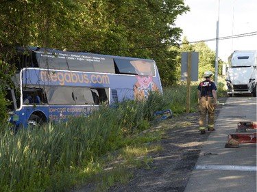 A firefighter attends the scene of an accident where dozens were injured, several seriously, when a tractor trailer and double-decker bus en route from Montreal to Kingston collided on highway 401 near Cornwall, Ont., on Tuesday, June 23, 2015.