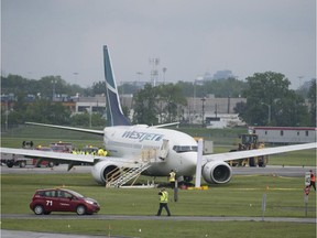 A WestJet plane sits in the grass at the end of the runway after it slid off the runway during heavy rains at Montreal's Trudeau airport Friday, June 5, 2015