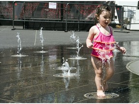 Nineteen-month-old Amalie Vallee-Assouad plays in a fountain to beat the 29C heat May 27, 2015 in Montreal.