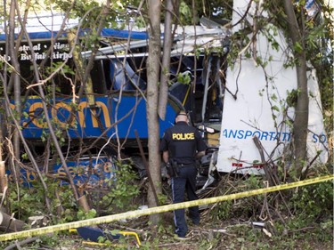 An OPP officer attends the scene of an accident where dozens were injured, several seriously, when a tractor trailer and double-decker bus en route from Montreal to Kingston collided on highway 401 near Cornwall, Ont., on Tuesday, June 23, 2015.