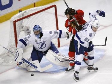 Chicago Blackhawks' Jonathan Toews, center, avoids Tampa Bay Lightning's Valtteri Filppula, of Finland, as Lightning goalie Ben Bishop, left, deflects a puck during the first period in Game 6 of the NHL hockey Stanley Cup Final series on Monday, June 15, 2015, in Chicago.