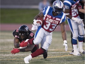 Alouettes running back Brandon Rutley (33) carries the ball as Ottawa Redblacks linebacker David Hinds (20) grabs his foot during second quarter of a CFL exhibition game Saturday, June 13, 2015, in Quebec City.
