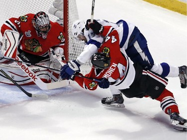 Chicago Blackhawks' Kimmo Timonen, front right, and Tampa Bay Lightning's Alex Killorn get tangled up as Blackhawks goalie Corey Crawford, left, watches during the first period in Game 4 of the NHL hockey Stanley Cup Final Wednesday, June 10, 2015, in Chicago.