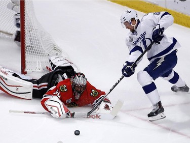 Tampa Bay Lightning's Anton Stralman reaches for a loose puck as Chicago Blackhawks goalie Corey Crawford, left, defends during the first period in Game 4 of the NHL hockey Stanley Cup Final Wednesday, June 10, 2015, in Chicago.