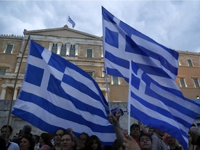 Demonstrators hold Greek flags during a rally organized by supporters of the YES vote to the upcoming referendum in front of the Greek Parliament in Athens June 30, 2015.