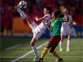 China's Wang Shanshan kicks the ball as she is pressured by Cameroon's Jeannette Yango during their FIFA Women's World Cup Group of 16 Match at Commonwealth Stadium in Edmonton, Canada on June 20, 2015. China defeated Cameroon 1-0.