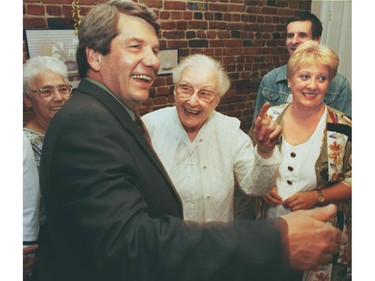 Georgette Bertrand, pointing, guides Jean Doré  as he meets people at a center for the elderly