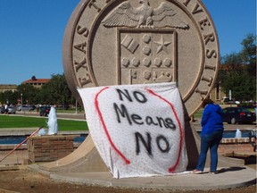 In this Wednesday, Oct. 1, 2014 file photo, Texas Tech freshman Regan Elder helps drape a bed sheet with the message "No Means No" over the university's seal at the Lubbock, Texas campus to protest what students say is a "rape culture" on campus.