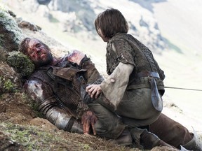 In this image released by HBO, an injured Sandor Clegane, better known as The Hound, portrayed by Rory McCann, left, and Arya Stark, portrayed by Maisie Williams, appear in a scene from Game of Thrones.