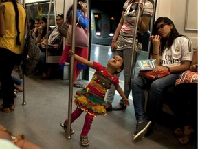 A young child plays as Indian commuters travel in the compartment reserved for women on the metro in New Delhi on June 10, 2015.