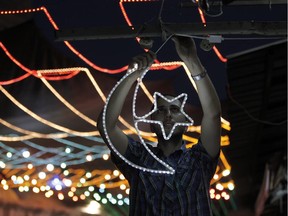 A Palestinian man decorates his shop with fairy lights near the entrance of the Al-Aqsa mosque compound, in the old city of Jerusalem on June 16, 2015, as Muslims around the world prepare for the announcement of the fasting month of Ramadan. Ramadan is expected to start on June 17 or 18 depending on the crescent moon.