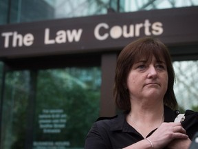 Former RCMP constable Janet Merlo, of Nanaimo, B.C., listens as lawyer David Klein speaks to reporters outside B.C. Supreme Court during a break in a hearing to seek certification of a class action lawsuit against the RCMP over sexual harassment and gender discrimination, in Vancouver, B.C., on Monday June 1, 2015.