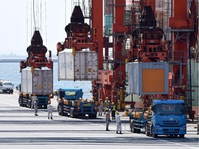 Gantry cranes unload containers from a cargo ship at a pier in Tokyo.