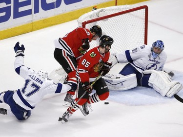 Tampa Bay Lightning goalie Ben Bishop (30) keeps his eye on a loose puck as Chicago Blackhawks' Jonathan Toews and Andrew Shaw (65) watch and Lightning's Alex Killorn (17) slides past during the first period in Game 6 of the NHL hockey Stanley Cup Final series on Monday, June 15, 2015, in Chicago.