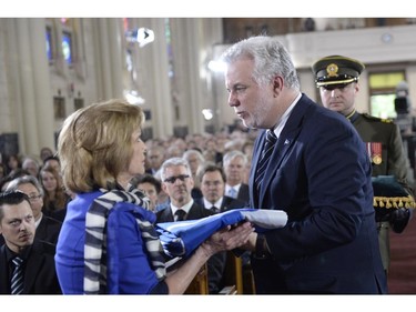 Quebec Premier Philippe Couillard presents widow Lisette Lapointe with Quebec flag which covered the casket of her late husband, former Quebec premier Jacques Parizeau, at his state funeral in Montreal on Tuesday, June 9, 2015.