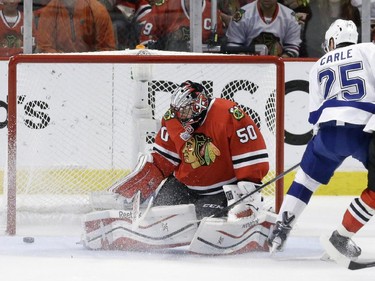 Tampa Bay Lightning's Matt Carle, right, and Chicago Blackhawks goalie Corey Crawford watch as a puck heads toward the post during the first period in Game 6 of the NHL hockey Stanley Cup Final Monday, June 15, 2015, in Chicago.
