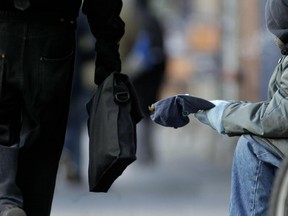 A street person waits with his hat out as people rush by in the cold along St.-Laurent Blvd. in Montreal .