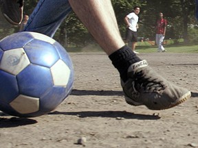 Montreal--06JUNE06--Nelson Arruda (left) dribbles the ball upfield chased by Yony Ordonez during multi-cultural pick-up soccer game on the dirt in Jeanne Mance Park Tuesday afternoon.  Arruda's team-mate Mariano Zacek waits for a pass at right.  Players at Jeanne Mance have been waiting for years for a safe soccer pitch with the City nearing completion of the new FieldTurf surface nearby.(Features)GAZETTE PHOTO BY JOHN MAHONEY