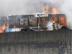 Firefighters work to extinguish a fire on a bus  engulfed in flames on the Ville-Marie expressway in Montreal on Thursday, April 23, 2015.