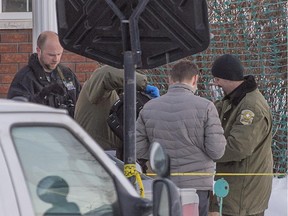 Police place what appears to be a backpack into an evidence bag at the home of a triple murder Trois-Rivières, February 11, 2014.