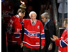 Former Montreal Canadiens great Jean Béliveau holds a torch prior to the start the opening game of the NHL season against the Toronto Maple Leafs at the Bell Centre Jan. 19, 2013.