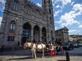 A horse carriage with tourists pass in front of the Notre-Dame Cathedral in Old Port in Montreal on Tuesday, July 30, 2013.