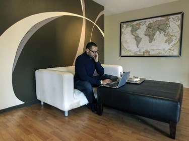 Ali Benryane in a sitting area in the open living room in his apartment in Little Burgundy.  The swirling motif on the wall was done by a friend who is an interior designer.  A framed National Geographic map of the world hangs on a wall, a nod to Ali's having lived in a number of countries and his job with the United Nations.