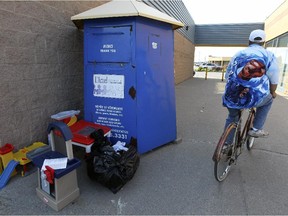 A man rides his bicycle past a box for charitable donations outside a shopping plaza on St-Charles Blvd. in Vaudreuil-Dorion on Saturday June 06, 2015.