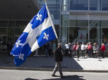 A mourner with a Quebec flag walks on the street during public visitation of former Quebec premier Jacques Parizeau, at the Caisse de dépôt et placement du Québec in Montreal, on Saturday June 6, 2015.