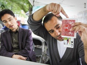 Travis Bernhardt watches as fellow magician Christian Cagigal performs a card trick in preparation for their shows at the Fringe Festival.