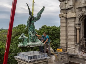Workers align the first of the two statues of angels that were removed from the Saint-Enfant-Jésus du Mile-End Church in 1978 and completely reconstructed from aluminium and copper and finally returned to their places on the Montreal church, on Friday, June 12, 2015.