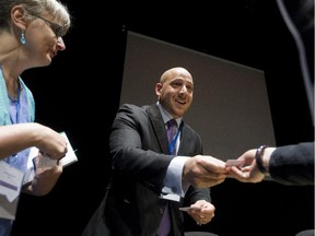 Kevin Hines gives business cards to Laura Eggerston, left, and others following his presentation at the International Association for Suicide Prevention congress at UQAM in Montreal, Tuesday, June 17, 2015.