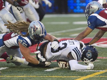 Montreal Alouettes Bear Woods, left and Chip Cox, right, bring down Toronto Argonauts Thomas Miles, during pre-season CFL football action in Montreal on Thursday June 18, 2015.