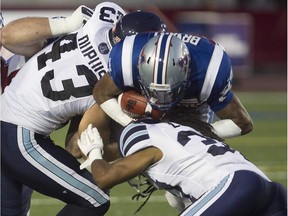 Montreal Alouettes Johnathan Bryant, goes over Toronto Argonauts Alexandre Dupuis, left,  and Jacob Lacey, right, during pre-season CFL football action in Montreal on Thursday June 18, 2015.