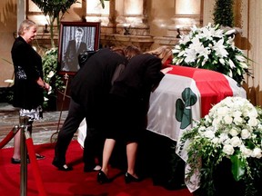 Christiane Sauvé, left, with her daughters Magali Doré and Amélie Duceppe kiss the coffin of Jean Doré after public visitation as he lies in state in the Hall of Honour at Montreal city hall on Sunday, June 21, 2015.
