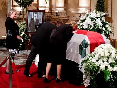 Christian Sauvé, left to right, looks on as her daughters Magali Doré and Amélie Duceppe kiss the coffin of Jean Doré after public visitation as he lies in state in the Hall of Honour at Montreal city hall on Sunday June 21, 2015.