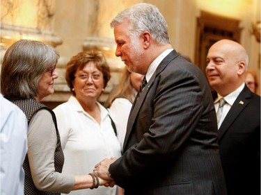 Quebec Premier Philippe Couillard and Robert Poeti, right, MNA for Marguerite-Bourgeoys, speak with people waiting to pay their respects to to Jean Doré as he lies in state in the Hall of Honour at Montreal city hall on Sunday June 21, 2015.