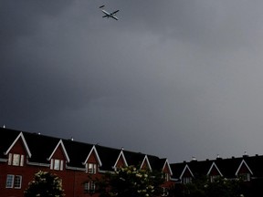 A plane preparing to land at Pierre Elliott Trudeau International Airport flies at low altitude over residential housing in the Saint-Laurent borough of Montreal on Wednesday June 24, 2015. A wheel fell from a plane and crashed into a home.