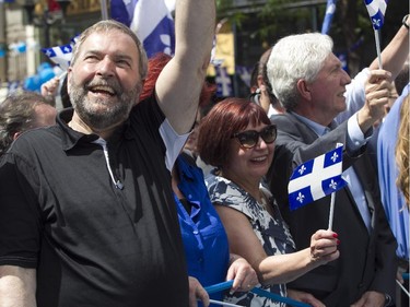 Thomas Mulcair (left), leader of the federal NDP party, beside Bloc Québécois leader Gilles Duceppe (right) and his wife Yolande Brunelle wave to people during the Fête nationale parade on Wednesday, June 24, 2015 in Montreal on St. Denis St.