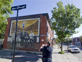 A Montreal police officer takes photographs a defaced mural honouring Beau Dommage, June 25, 2015.