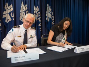 Marc Parent, head of the SPVM, signs a document alongside Nakuset, co-president of the RESEAU pour la strategy urbane de la communauté autochtone a Montréal, during a press conference to sign an agreement between the native community of Montreal and Montreal police at the SPVM headquarters in Montreal.