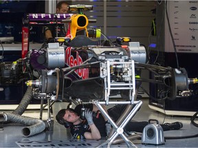 Red Bull technicians work on the car belonging to Daniil Kvyat in the team's garage ahead of the Canadian Grand Prix at Circuit Gilles Villeneuve in Montreal on June 4, 2015.