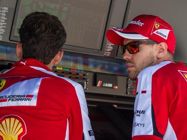 Ferrari Formula 1 driver Sebastian Vettel of Germany, right, speaks with a team technician after the qualifying session for the F1 Canadian Grand Prix at Circuit Gilles-Villeneuve in Montreal on Saturday, June 6, 2015.