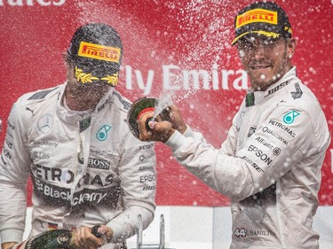 Mercedes Formula 1 driver Lewis Hamilton of Great Britain, right, celebrates his first place finish in the F1 Canadian Grand Prix along with teammate Mercedes Formula 1 driver Nico Rosberg of Germany, left, at Circuit Gilles-Villeneuve in Montreal on Sunday, June 7, 2015. Williams Formula 1 driver Valtteri Bottas of Finland came in third.