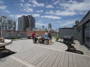 Rooftop terrace of Coopérative Cercle Carré on Queen Street in Montreal.  The building is a seven-storey concrete and steel building that was converted into and artists' housing cooperative in 2010. They wanted to use the flat roof of the building for events and urban agriculture, so they hired architect Owen Rose to design a green roof and a wooden terrace with river rocks surrounding it.