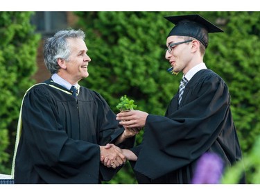 John Halpin, Director General of John Abbott College, congratulates a student, presenting him a gift of a spruce seedling, at convocation ceremonies held outdoors in front of the Hertzberg Building, in Ste. Anne-de-Bellevue, Quebec on June 11, 2015. Established in 1971, some  2,000 students graduated, with 425 diplomas and honours certificates being awarded.