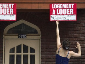 A woman reaches up to remove a for rent sign in Montreal, July 1, 2014.