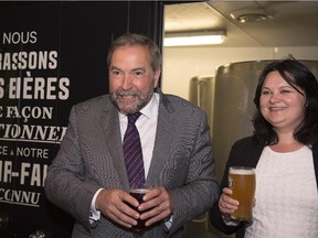 NDP Leader Tom Mulcair enjoys a beer with local candidate Annick Papillon, right, at a microbrewery in Quebec City, Tuesday, June 23, 2015.